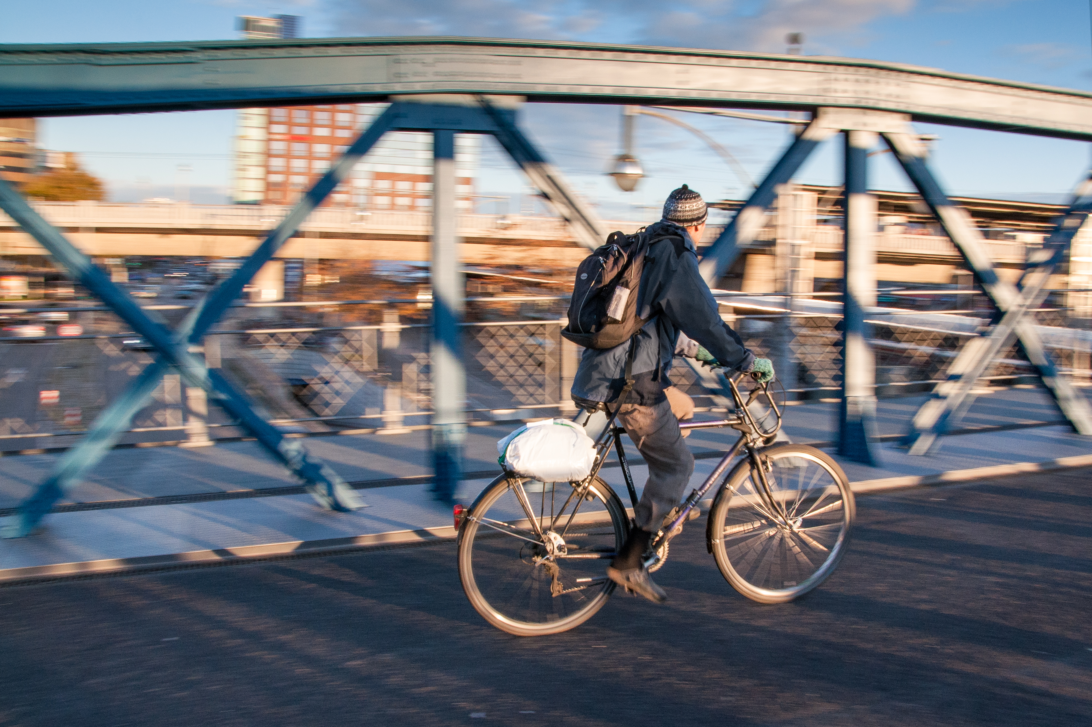 person riding bicycle beside gray metal railings of bridge